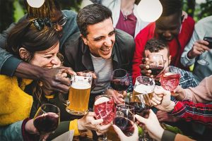 Friends toasting drinks at a festive holiday party while celebrating responsibly and supporting natural liver health.
