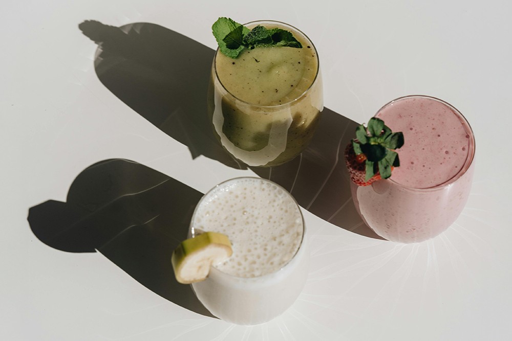 Three refreshing summer smoothies made with fruit and superfoods in glass cups