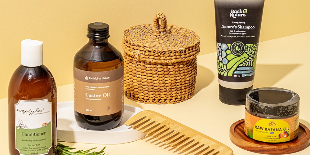Natural haircare products including castor oil, conditioner, shampoo, wooden comb and hair mask styled for summer haircare.