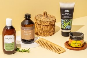 Natural haircare products including castor oil, conditioner, shampoo, wooden comb and hair mask styled for summer haircare.